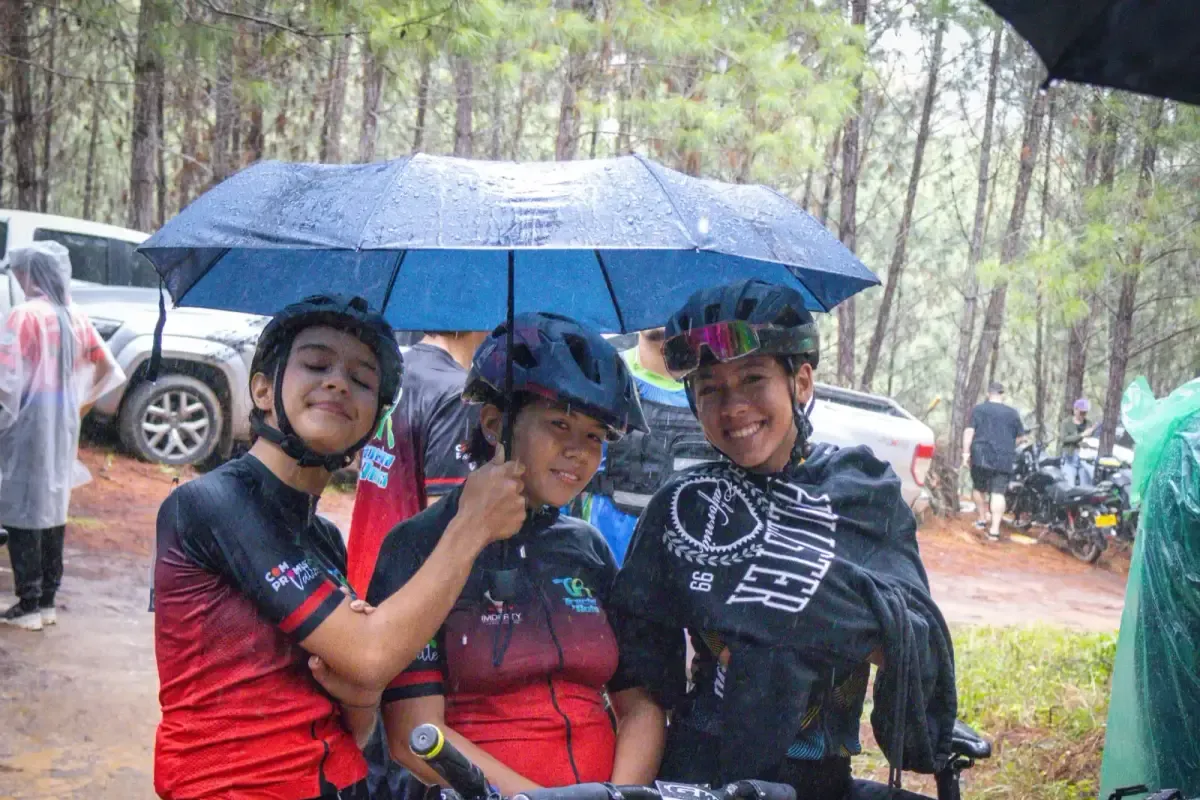 Tres deportistas del club sonriendo bajo la lluvia en una válida de la Copa Valle