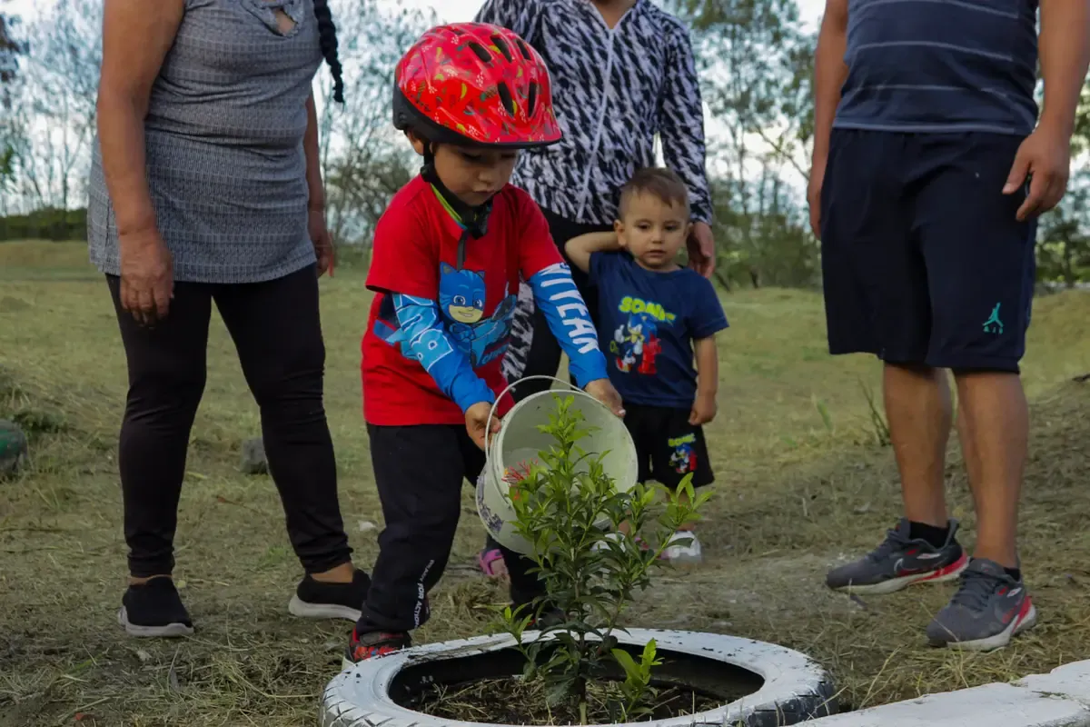 Niño del club regando un árbol recién sembrado en la pista durante la Sembratón