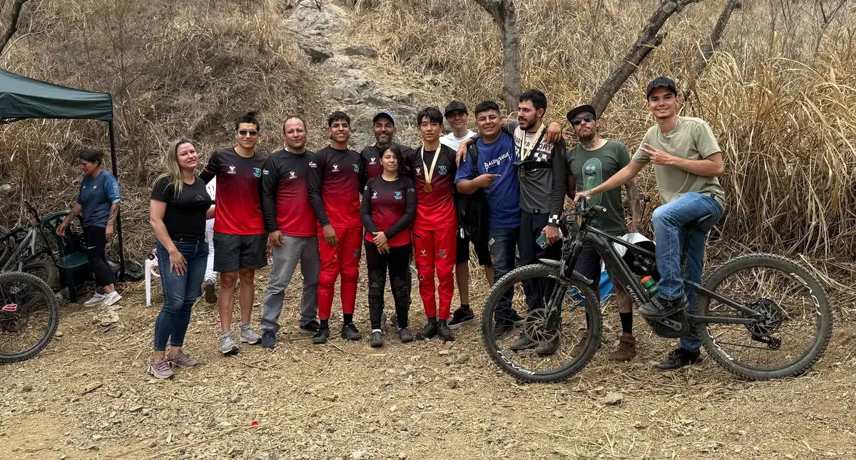El equipo del Club Trocha y Ruta con padres, profesores, director deportivo, deportistas y amigos al pie de una pista de roca en el Cali Bike Park; en el centro, Samuel Ortiz con su medalla