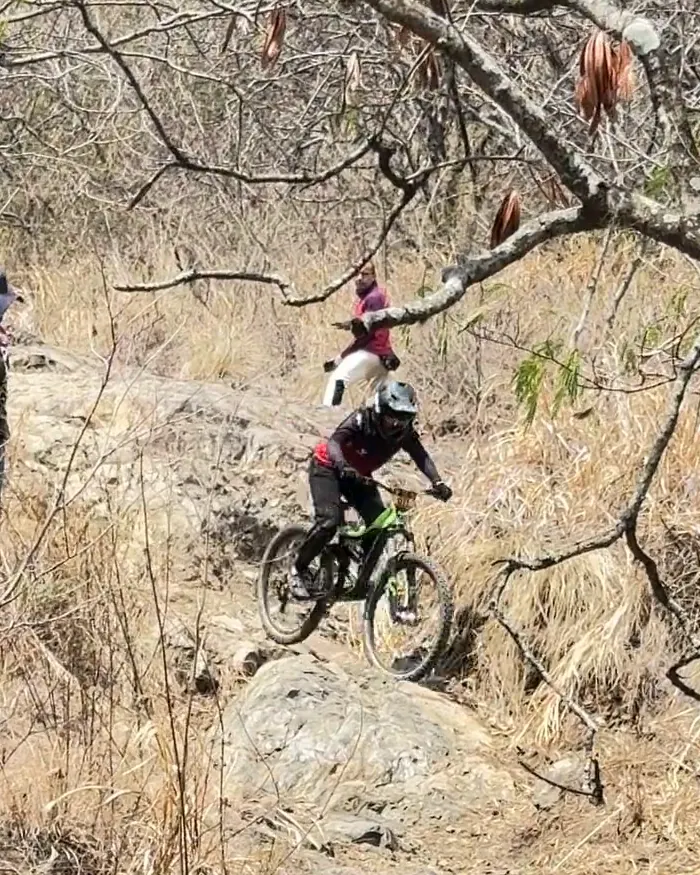 Isabel Quiñones del Club Trocha y Ruta baja en la bicicleta verde por una ladera de roca bajo las ramas de un árbol, Copa Cali Bike Park, 2026