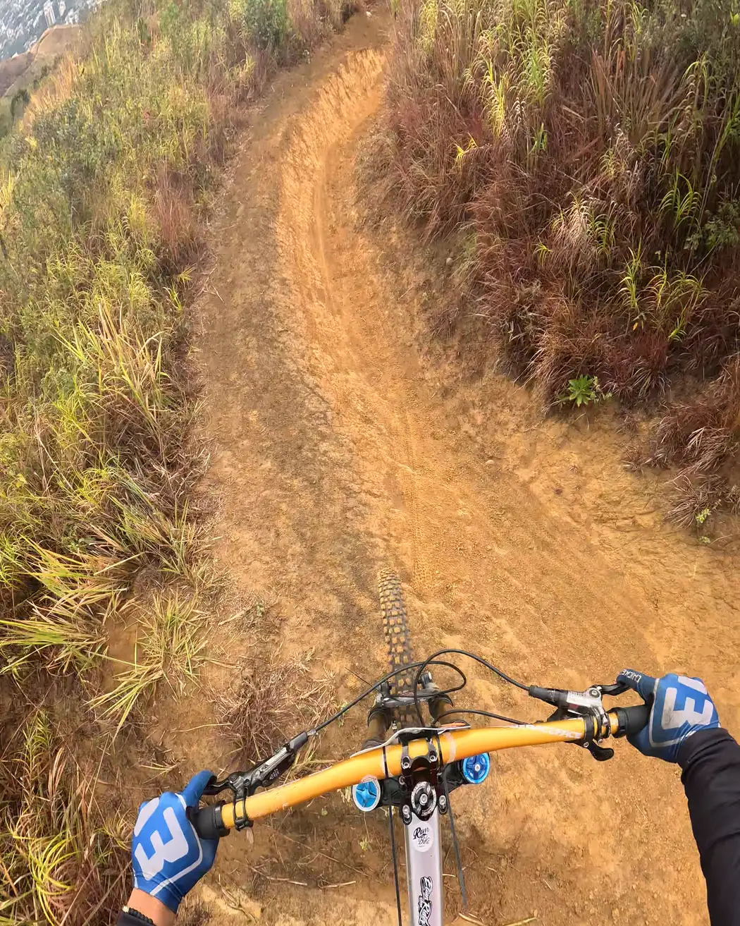 Vista desde el manubrio: una curva de tierra anaranjada con la ciudad al fondo, Cali Bike Park, 2026