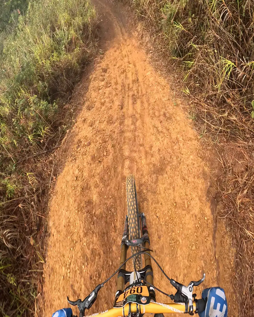 Vista desde el manubrio: un lomo de tierra anaranjada entre pasto, Cali Bike Park, 2026