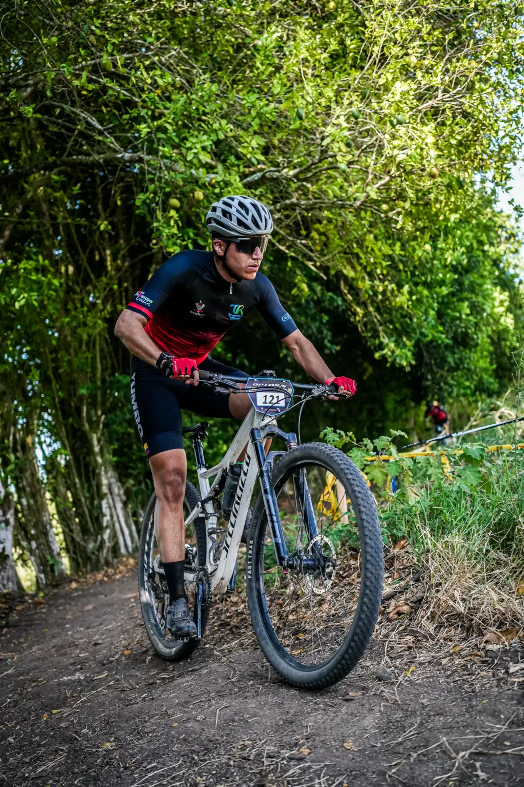 Juan Diego García del Club Trocha y Ruta, con el dorsal 121, pedalea por un sendero entre árboles en el circuito de la Copa Let's Go Interdepartamental XCO, Alcalá, 2026