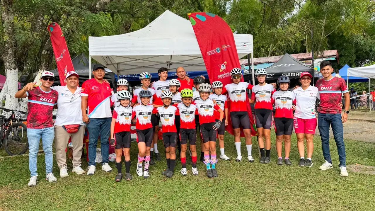 La delegación de la Selección Valle del Cauca de ciclomontañismo, con corredores y cuerpo técnico, posa frente a la carpa de Indervalle en el Parque Metropolitano del Café